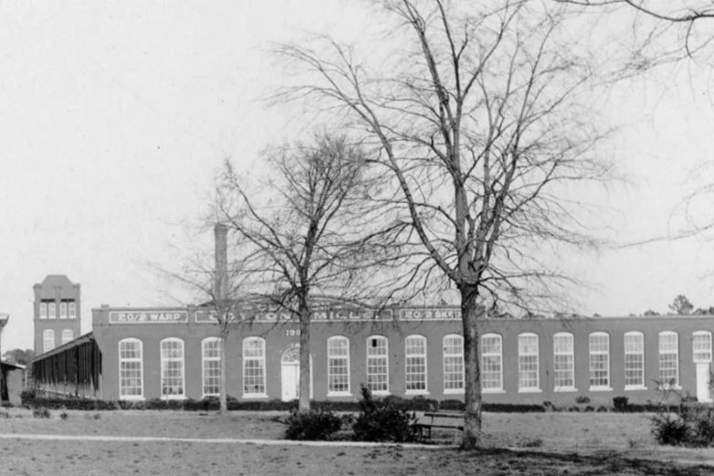 The Clayton spinning mill about 1920: a long brick building with arched windows and a smokestack behind it
