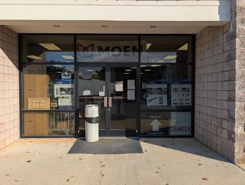 The glass front entrance with a MOEN sign and a sign pointing to the parts counter