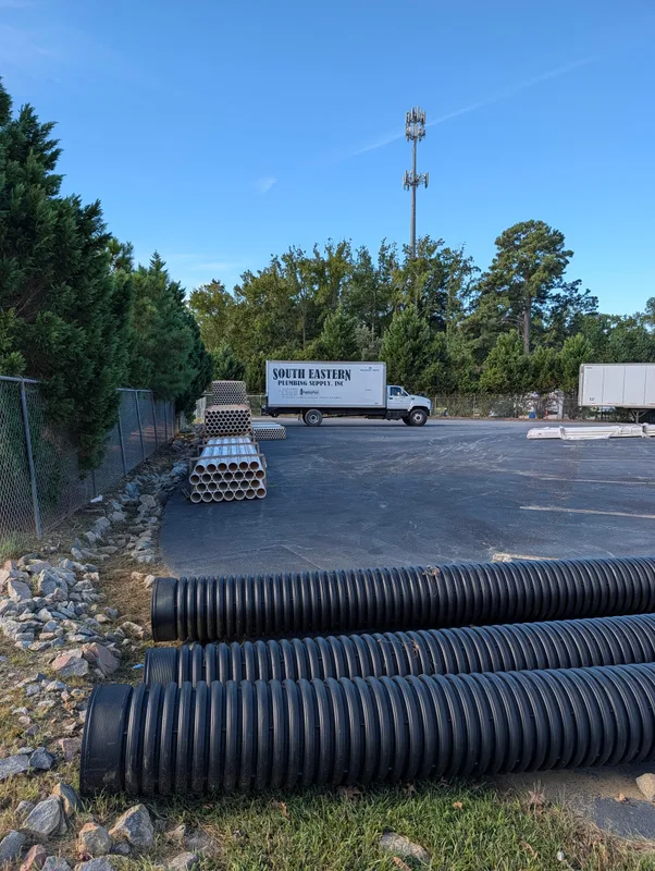 Black corrugated pipe in the yard, with a South Eastern box truck behind