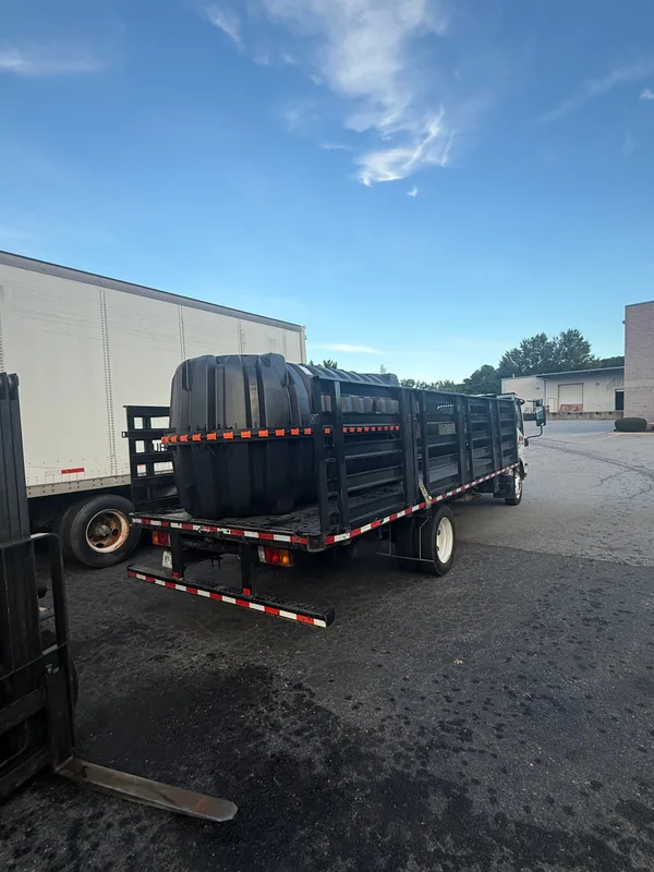 A large black tank strapped on the flatbed in the lot
