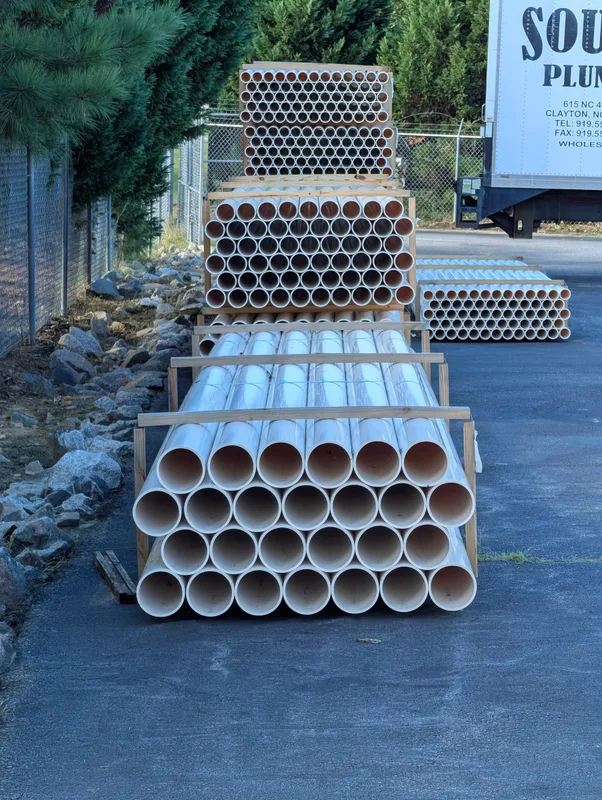 Stacks of large white pipe in the yard beside the warehouse