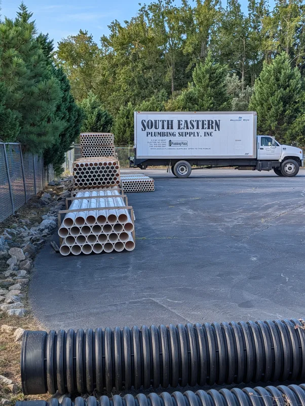 Corrugated and white pipe in the yard with a South Eastern box truck parked behind
